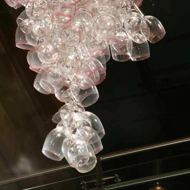 Here Come the Girls 2009
Manchester Art Gallery Atrium
1100 Wine Glasses
Lipstick
Commissioned by Manchester Art Gallery to celebrate the festive season and specifically to link to their exhibition Angels of Anarchy: Women Artists and Surrealism. The primary reference is to Meret Oppenheim's iconic fur teacup, saucer and spoon, Object. In a contemporary culture where women are just as likely to drink wine as tea the vessel still functions as a metaphor for the female body, but in the 21st century sexual politics have evolved.
Each glass is individually rimmed with lipstick using the artist's lips. Cosmetics, particularly lipstick, are often advertised as a way to enhance feminine power and choice, and one cosmetic company even used the slogan 'It's not makeup, it's ammunition'.
<em>"While thinking of 'strong women' femininity, power and Christmastime, I was reminded of the recent Boots TV commercials with crowds of women getting glammed up and marching out to celebrate to the Sugababes 'Here come the Girls'."</em> Susie MacMurray
The work offers a space for rumination on the evolution of feminism and perceptions of female power/empowerment in it's various guises – cultural/political/sexual. Also on the different ways women choose to exercise that empowerment (including binge drinking), the ambiguities it throws up, and psychological bargains we strike with ourselves.