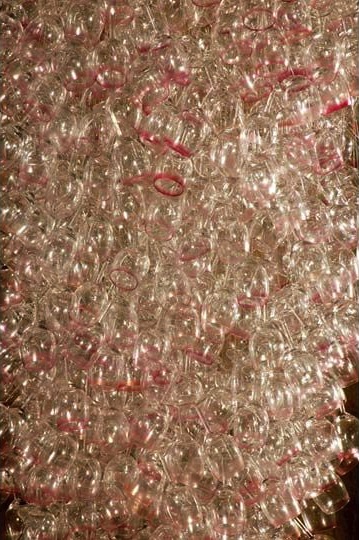 Here Come the Girls 2009
Manchester Art Gallery Atrium
1100 Wine Glasses
Lipstick
Commissioned by Manchester Art Gallery to celebrate the festive season and specifically to link to their exhibition Angels of Anarchy: Women Artists and Surrealism. The primary reference is to Meret Oppenheim's iconic fur teacup, saucer and spoon, Object. In a contemporary culture where women are just as likely to drink wine as tea the vessel still functions as a metaphor for the female body, but in the 21st century sexual politics have evolved.
Each glass is individually rimmed with lipstick using the artist's lips. Cosmetics, particularly lipstick, are often advertised as a way to enhance feminine power and choice, and one cosmetic company even used the slogan 'It's not makeup, it's ammunition'.
<em>"While thinking of 'strong women' femininity, power and Christmastime, I was reminded of the recent Boots TV commercials with crowds of women getting glammed up and marching out to celebrate to the Sugababes 'Here come the Girls'."</em> Susie MacMurray
The work offers a space for rumination on the evolution of feminism and perceptions of female power/empowerment in it's various guises – cultural/political/sexual. Also on the different ways women choose to exercise that empowerment (including binge drinking), the ambiguities it throws up, and psychological bargains we strike with ourselves.