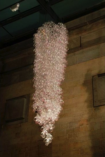 Here Come the Girls 2009
Manchester Art Gallery Atrium
1100 Wine Glasses
Lipstick
Commissioned by Manchester Art Gallery to celebrate the festive season and specifically to link to their exhibition Angels of Anarchy: Women Artists and Surrealism. The primary reference is to Meret Oppenheim's iconic fur teacup, saucer and spoon, Object. In a contemporary culture where women are just as likely to drink wine as tea the vessel still functions as a metaphor for the female body, but in the 21st century sexual politics have evolved.
Each glass is individually rimmed with lipstick using the artist's lips. Cosmetics, particularly lipstick, are often advertised as a way to enhance feminine power and choice, and one cosmetic company even used the slogan 'It's not makeup, it's ammunition'.
<em>"While thinking of 'strong women' femininity, power and Christmastime, I was reminded of the recent Boots TV commercials with crowds of women getting glammed up and marching out to celebrate to the Sugababes 'Here come the Girls'."</em> Susie MacMurray
The work offers a space for rumination on the evolution of feminism and perceptions of female power/empowerment in it's various guises – cultural/political/sexual. Also on the different ways women choose to exercise that empowerment (including binge drinking), the ambiguities it throws up, and psychological bargains we strike with ourselves.